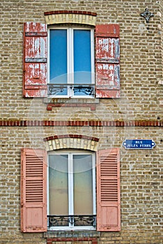 Vertical shot of a building facade with old windows with wooden shutters, France