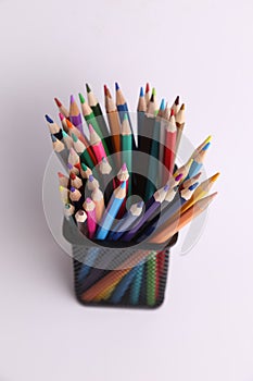 Vertical shot of a bunch of colorful pencils on metal holder isolated on white background