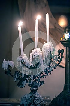 Vertical shot of burning candles on an old candelabra in a room