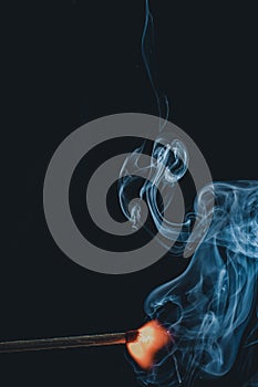 Vertical shot of a burning match with abstract smoke clouds