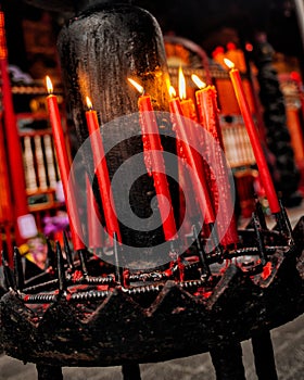 Vertical shot of burning red candles inside a church on a blurred background