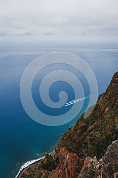 Vertical shot of Camara Lobos on the island of Madeira with clean, blue water and a cloudy sky