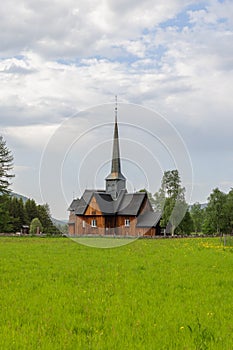 Kvikne kirke's towering spire rises in greenery, blending history with pastoral charm