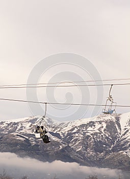 Vertical shot of chairlift in the snow, with snowy mountains in the background - winter ski resort