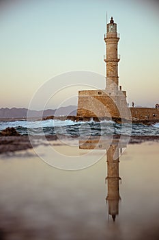 Vertical shot of the Chania Lighthouse in Crete, Greece reflecting on a puddle of water