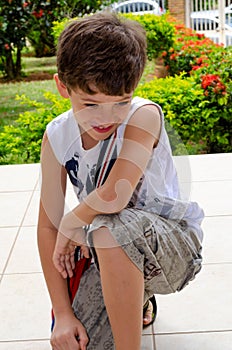 Vertical shot of a cheerful caucasian boy kneeled on the ground
