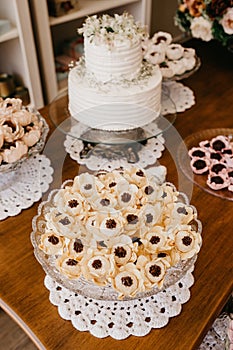 Vertical shot of chocolate candies with nuts in decorative flower buds and delicious white cake