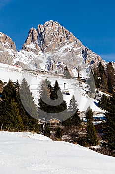 Vertical shot of the Cima Uomo Mountain in the Dolomites with ski lift and log cabin photo