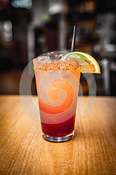 Vertical shot of a classic margarita cocktail with a slice of lime and salty rim on bar counter