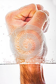 Vertical shot of closed fist submerge into soda water isolated on white background