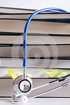 Vertical shot.Closeup of pile of medical books and stethoscope