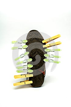 Vertical shot of clothespins clipped to a sneaker isolated on the empty white background