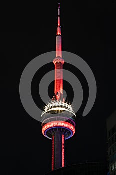 Vertical shot of the CN tower at night with reflecting sparkly lights