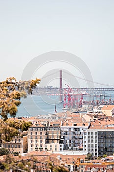 Vertical shot of coastal houses with the Ponte 25 de Abril bridge in a background in Lisbon,Portugal