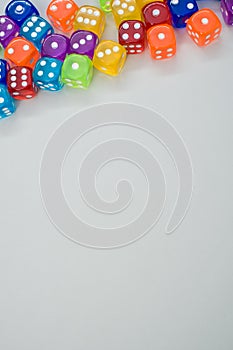 Vertical shot of colorful plastic dice on a gray surface with space for text