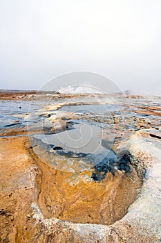 Vertical shot of Colorful and textured volcanic ground in geothermal area in Icelandic scenery towards steam vents.