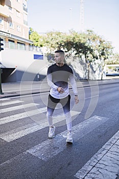 Vertical shot of a cool young man posing walking on the street wearing activewear