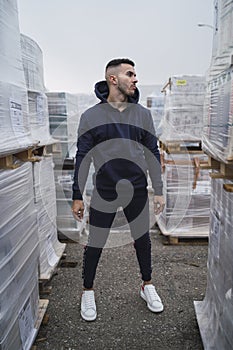 Vertical shot of a cool young man wearing a hoodie and sweatpants standing near new furniture