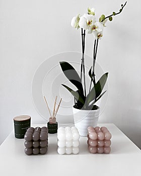 Vertical shot of cube candles, incense, and a potted orchid on a shelf