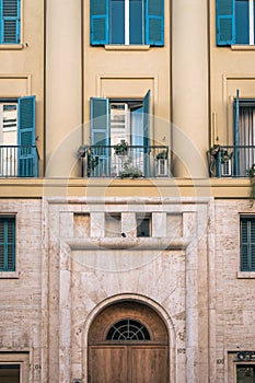 Vertical shot of a cute building with yellow walls and blue windows with balconies