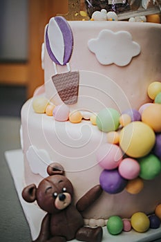 Vertical shot of a cute two layer cake with colorful marzipan calls and a marzipan bear
