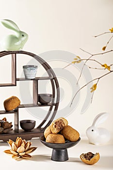 Vertical shot of a decorative shelf with cups, a ceramic rabbit, traditional Chinese mooncakes