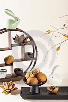 Vertical shot of a decorative shelf with cups, a ceramic rabbit, traditional Chinese mooncakes