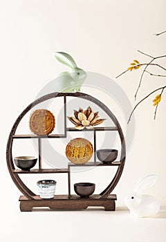 Vertical shot of a decorative shelf with cups, a ceramic rabbit, traditional Chinese mooncakes