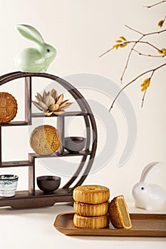 Vertical shot of a decorative shelf with cups, a ceramic rabbit, traditional Chinese mooncakes
