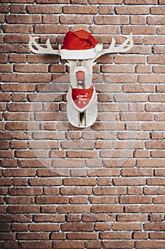 Vertical shot of a deer hanging on the wall with a Santa Claus cap and red necklace