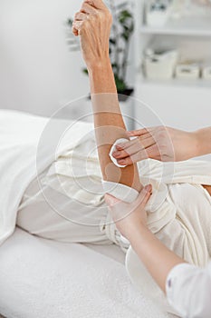 Vertical shot of dermatologist hands cleaning female arm skin applying cleanser and tonic