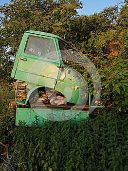 Vertical shot of dismounted parts of a vintage truck on a meadow