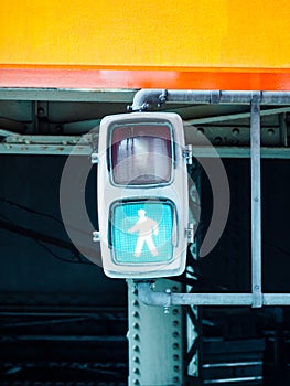 Vertical shot of an electric pedestrian crosswalk sign with green light signalling to cross the road