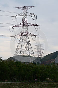 Vertical shot of electric power towers in a green field in Sheung Shui, Hong Kong