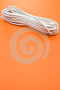 Vertical shot of an electrical extension cord isolated on orange background
