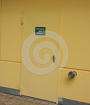 Vertical shot of an emergency exit sign in the German language on a yellow door