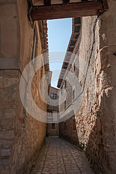 Vertical shot of an empty narrow European street with stone walls and house windows