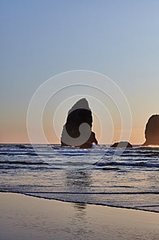 Vertical shot of the famous Haystack Rock on the rocky shoreline of the Pacific Ocean