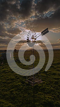 Vertical shot of a farm windmill in a field under the white clouds in Australia