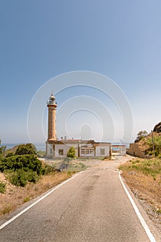 Vertical shot of the Faro Punta Carnero lighthouse near a road in Spain photo