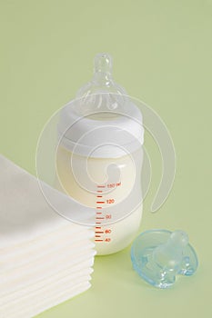 Vertical shot of a feeding bottle with baby food, pacifier and disposable towels