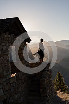 Vertical shot of a female standing on a building with a black skirt wavering in the wind