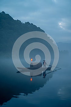 Vertical shot of a fisherman on a picturesque misty lake in Chenzhou,China