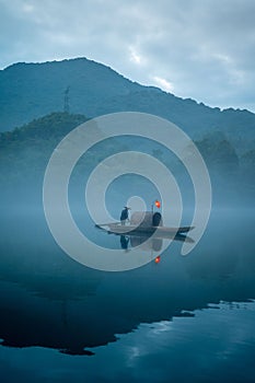 Vertical shot of a fisherman on a picturesque misty lake in Chenzhou,China