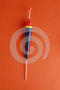 Vertical shot of a fishing lure on an orange background