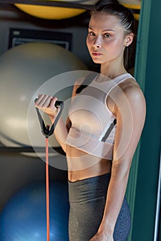 Vertical shot of fit young woman exercising with resistance band in the gym. Athelte girl working with elastic band in the fitness