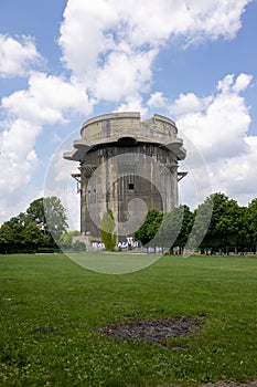 Vertical shot of a Flak tower surrounded by trees under the cloudy blue sky in Vienna, Austria