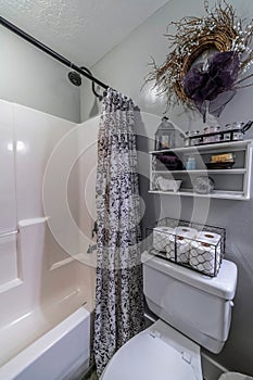 Vertical shot of a flush toilet with an open-curtained bathtub