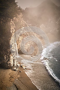 Vertical shot of foggy McWay Falls waterfall on the coast of Big Sur in central California
