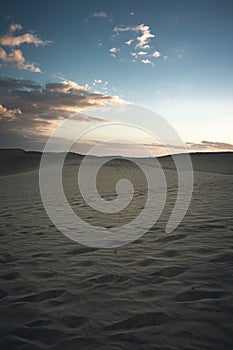 Vertical shot of footprints on sand dunes in a desert on Grand Canary Island during sunrise